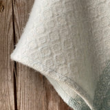 Tirkīzzila toņa īsais/pusgarais aitas vilnas pončo ar baltām bārkstīm