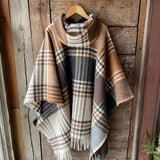 Klasiskas rūtis karameļi brūnos/pelēkos/baltos toņos indiāņu piegriezuma garais aitas vilnas pončo ar kapuci un bārkstīm