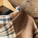 Klasiskas rūtis karameļi brūnos/pelēkos/baltos toņos indiāņu piegriezuma garais aitas vilnas pončo ar kapuci un bārkstīm